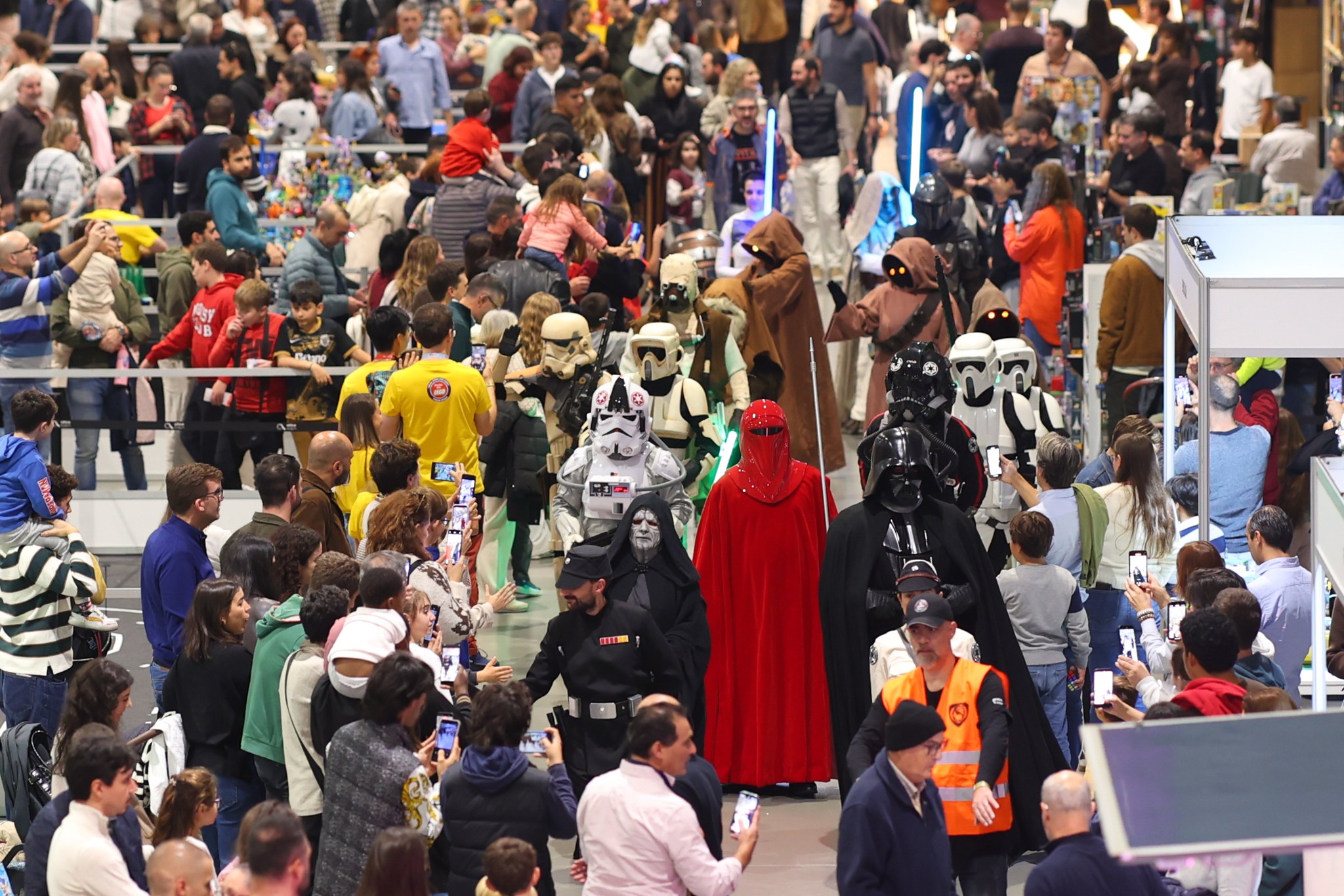 Desfile de personagens de Star Wars entre os visitantes de um evento.