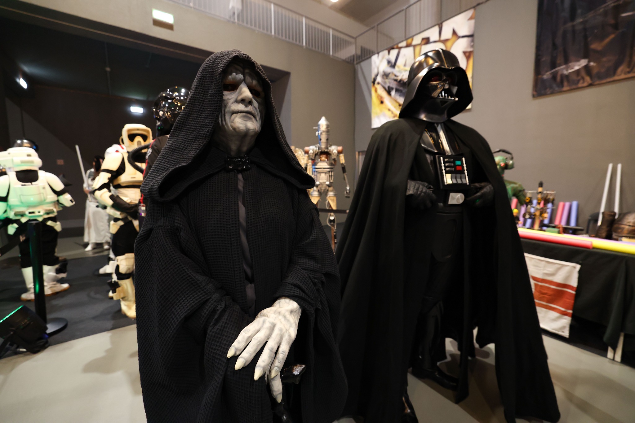 Participantes com fatos do Imperador Palpatine e de Darth Vader num evento.